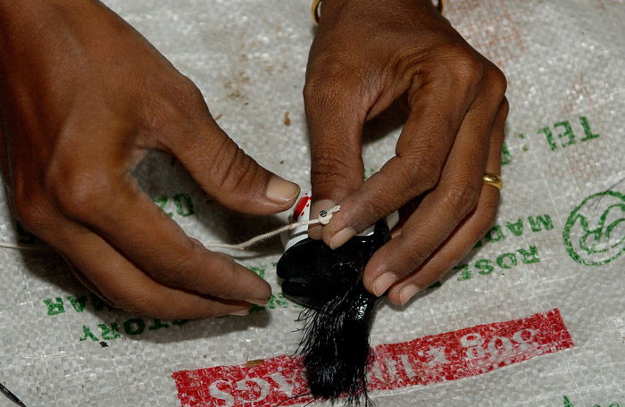 Overhead view of a hand painting a doll heads showing a sense of scale in photography