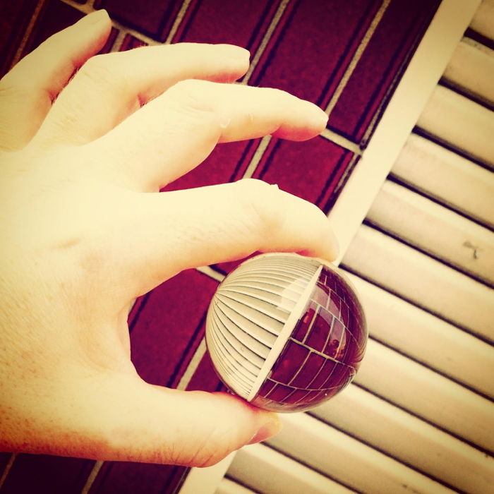 A person holding a crystal ball reflecting abstract architectural elements 