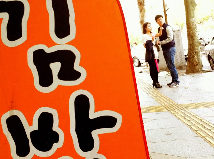 韩国的一张街头照片，上面有一个标志和一对夫妇