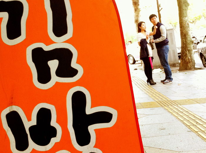 A street photo in south Korea featuring a sign and a couple 