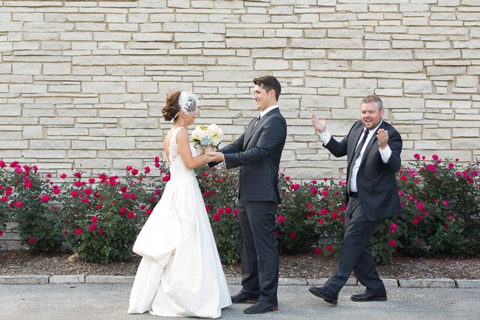 Humorous portrait of a newlywed couple was having their first look with the best man rushing in to goof it up for them - the decisive moment in photography