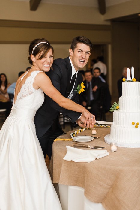 Fun wedding porttrait of the newlyweds cutting the cake
