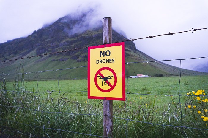 A sign reading no drones in a green landscape