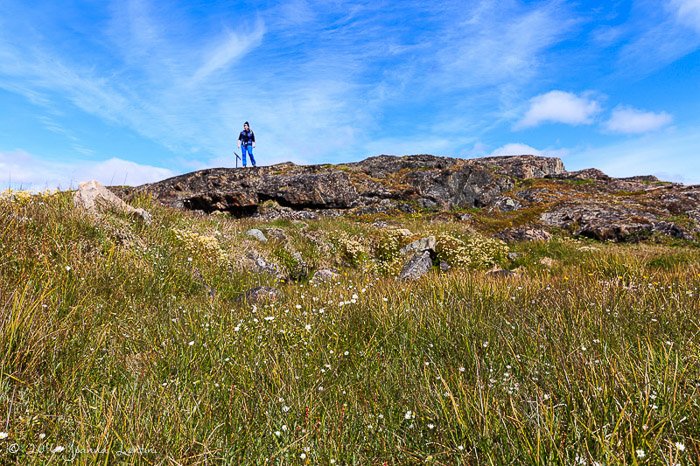 A female photographer standing on a rock on a clear day - adventure photography gear