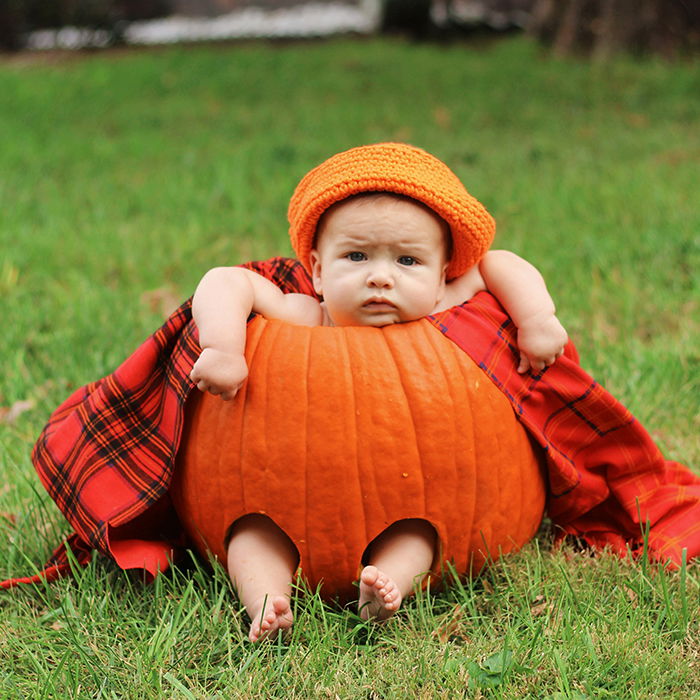 Adorable autumn portrait of a baby in a pumpkin