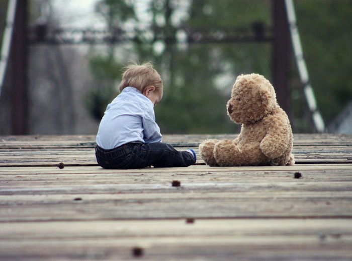 A small child sitting with a teddy bear 