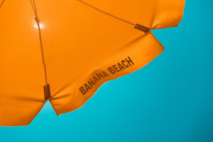 An orange parasol sits in front of a inviting blue sky