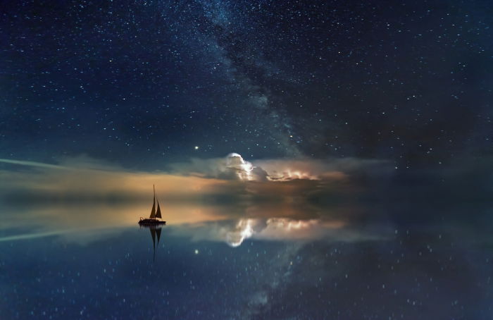 An edited image of a sailboat floating in the sea with a starry sky