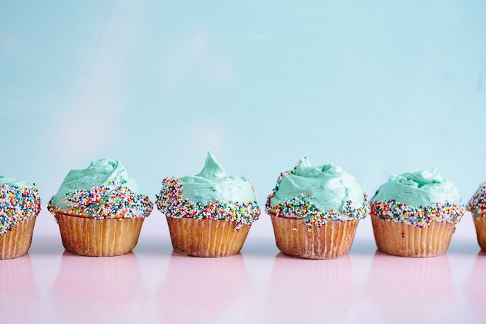 A line of green frosted cupcakes against a light background