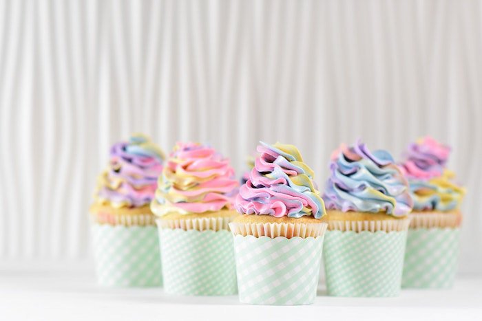 Bright and airy photoshot of five colorful cupcakes against a light background