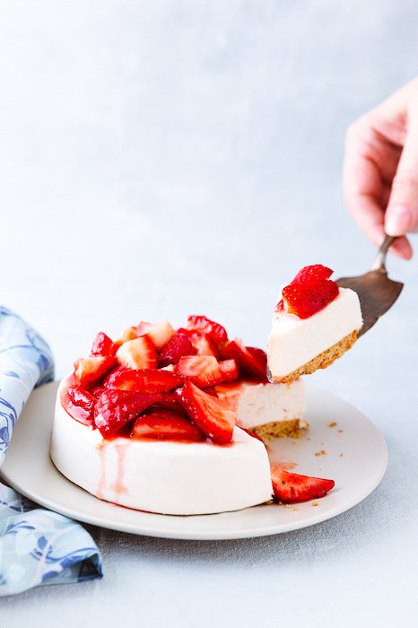 A bright and airy shot of a cake topped with strawberries