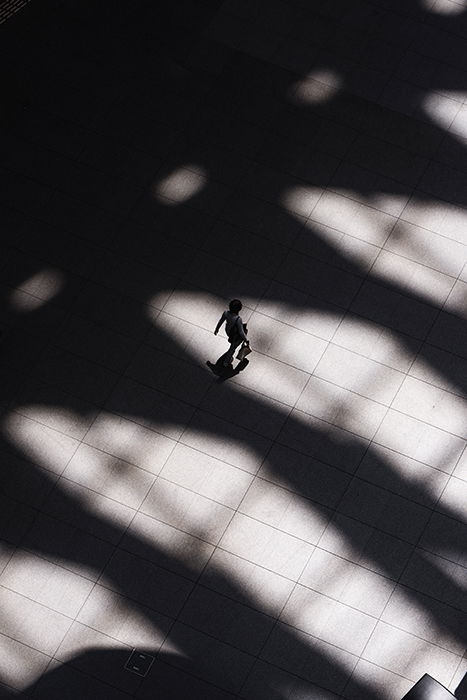 Aerial photo of a person walking among heavy shadows on stone path - form photography