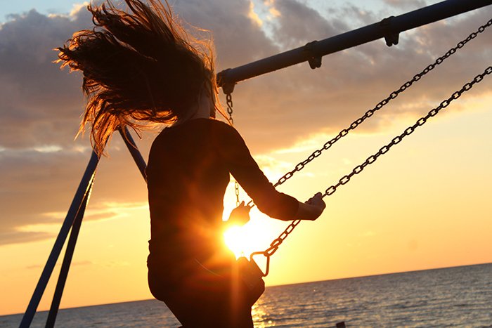 Atmospheric portrait of a girl swinging on a swing set at sunset - form in photography