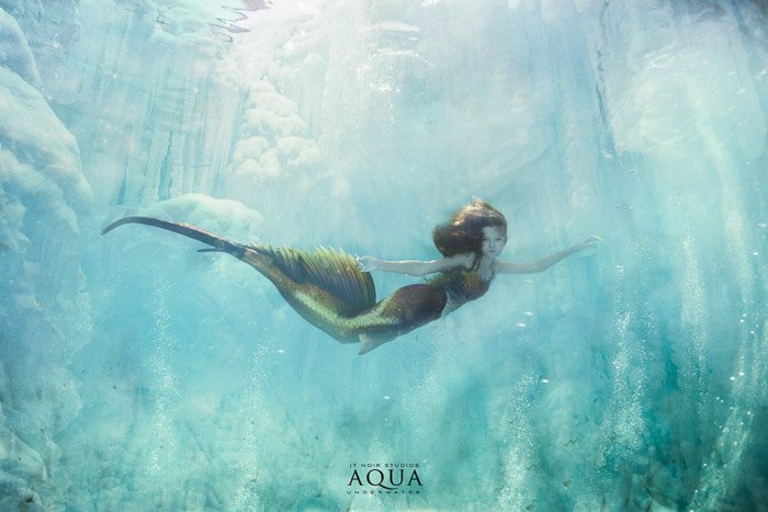 A magical underwater mermaid photoshoot featuring a female model with mermaid tail swimming underwater