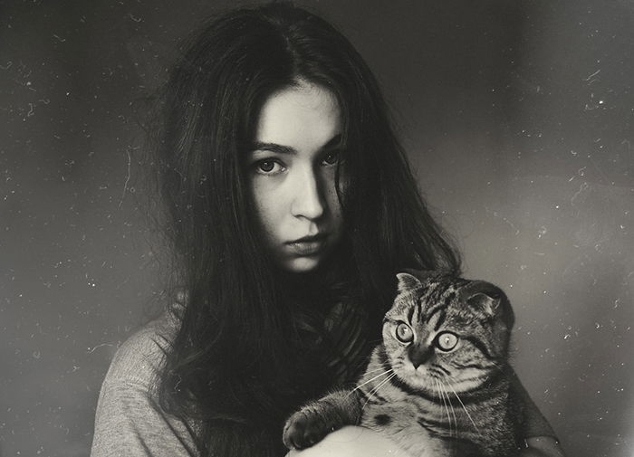 A film noir inspired grainy portrait of a girl holding a cat