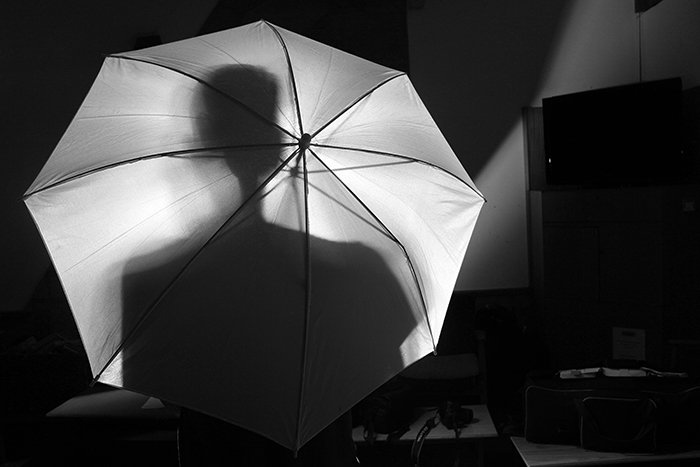 Monochrome shot of the silhouette of a person behind an umbrella