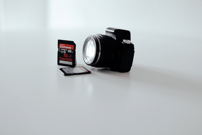 A camera and two memory cards on white background - photography business equipment