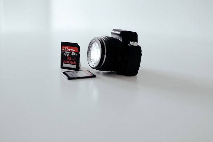 A camera and two memory cards on white background - photography business equipment