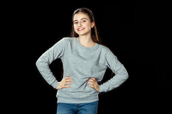 A school portrait of a female student posing casually against black background 