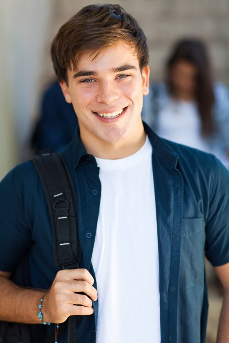 A school portrait of happy male high school student smiling in a school corridor - tips for quality school portraits