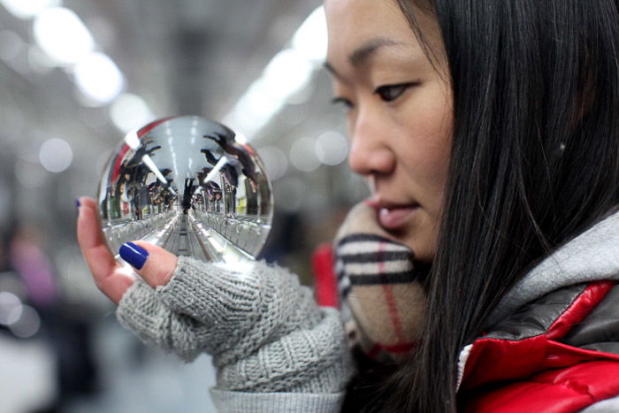 Urban portrait of a female model gazing into a crystal ball on a subway train