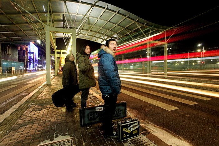 Urban portrait of three people waiting for public transport at night