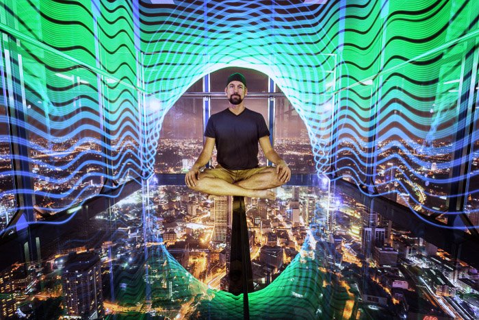 A surreal urban portrait of a man levitating over a night cityscape surrounded by neon lights