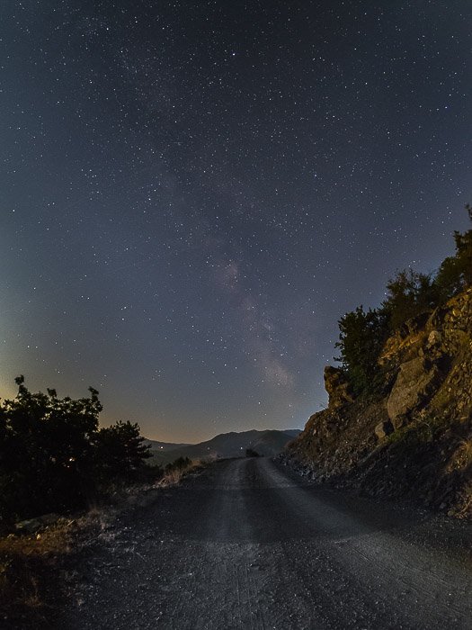 A country road at night under a star filled sky 