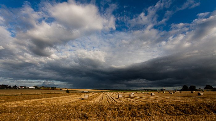 A typical wide angle landscape shot of a field under a cloudy sky 