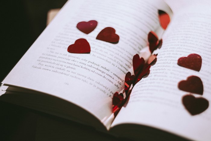 Artistic still life of heart shaped confetti scattered on the pages of a book - fine art wedding photography 