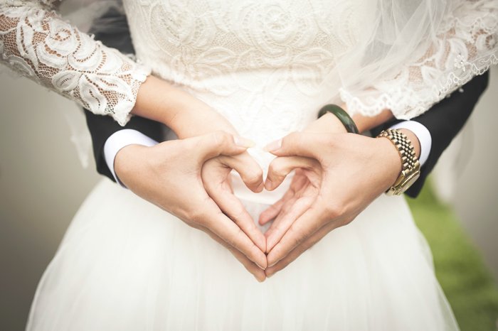 Artistic close up portrait of a newlywed couple holding each others hands in a heart shape - fine art wedding photography 