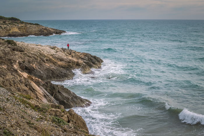 A beautiful coastal landscape with focus on a man in red jacket