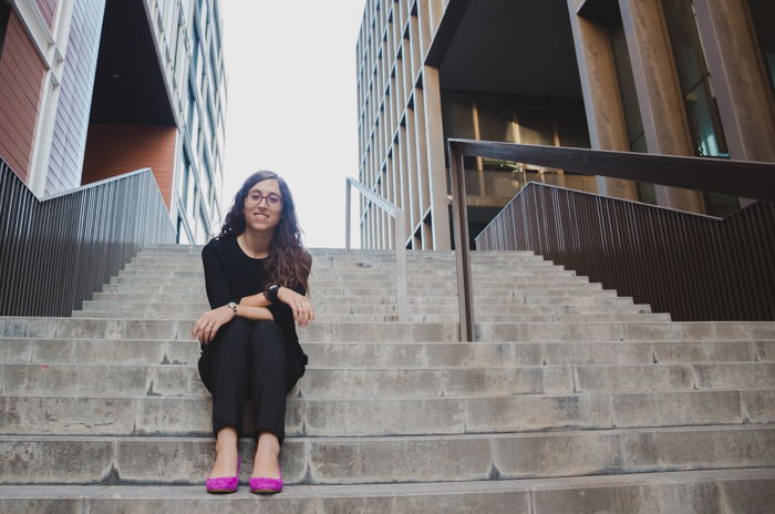 A female model in pink shoes sitting on stone steps