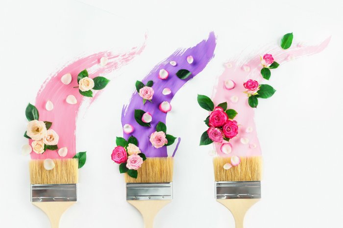 a minimalist flat lay with brushes or paint rollers covered with different types of newborn flowers