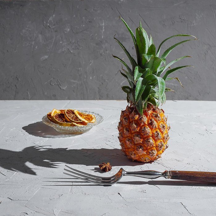 Artistic still life featuring a pineapple and a plate of oranges shot with a speedlight
