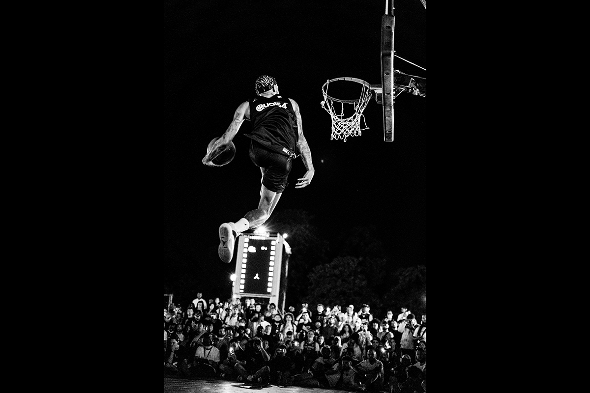 A player about to slam dunk on a court outside at night as an example of basketball photography
