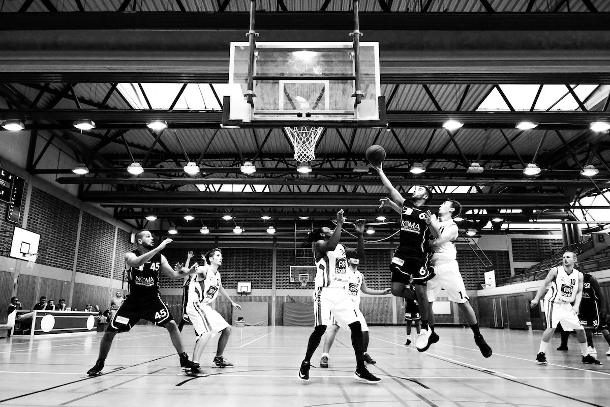 A wide-angle shot of a basketball game in black and white