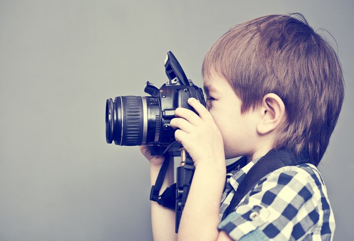 Sweet portrait of a young boy holding a DSLR camera 