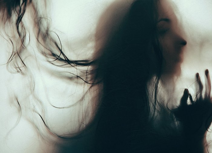 Atmospheric blurry portrait of a moody female model with hair covering her face - examples of dark portraits