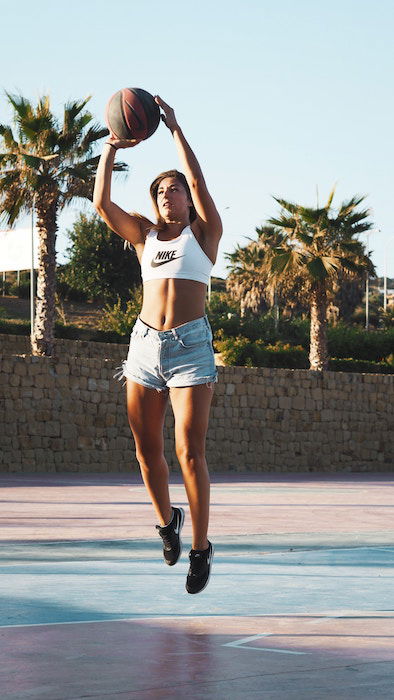 a portrait of a female basketball player jumping with the ball - basketball photoshoot 