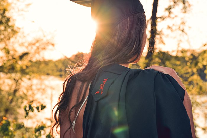 Beautiful candid graduation portrait of a female student outdoors in a forest
