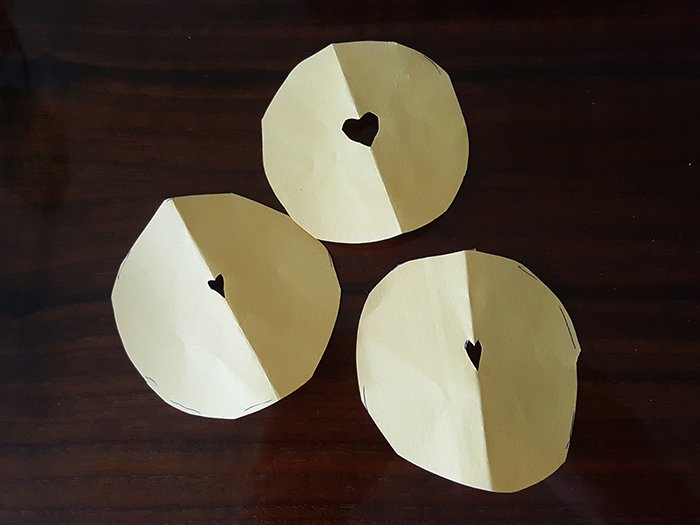 Three paper circles with a heart-shaped hole to make heart bokeh filters