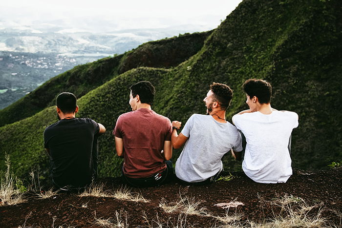 Four friends sitting among a beautiful mountainous landscape - lifestyle portraits