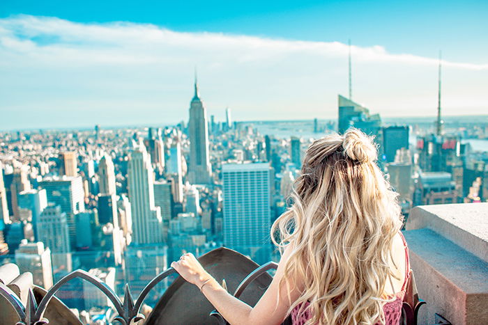 A blonde model posing on a rooftop gazing out at a sprawling cityscape - lifestyle portraits