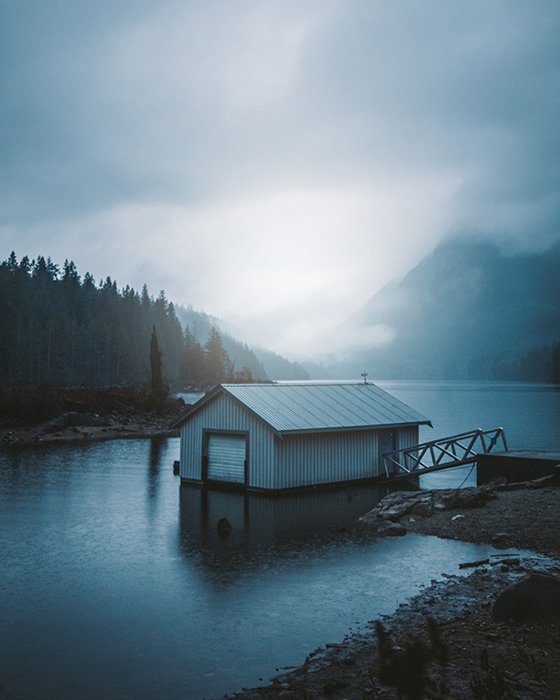 A boat shed in a lake among a beautiful mountainous landscape in blue light