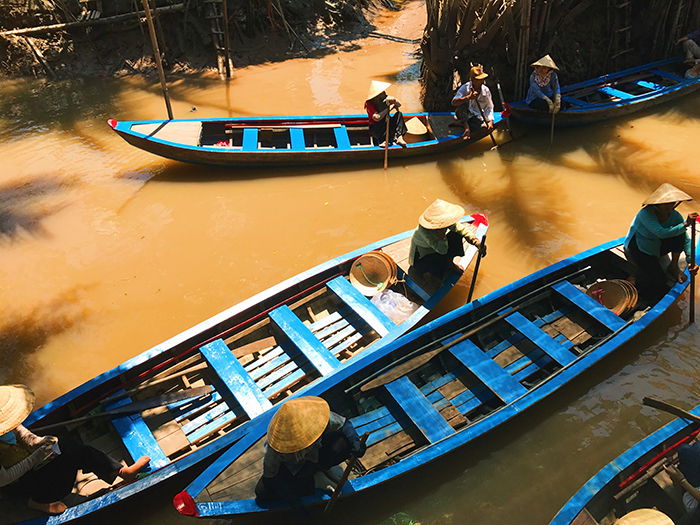 Overhead shot of people rowing wooden boats in a river - best quality of light for the day