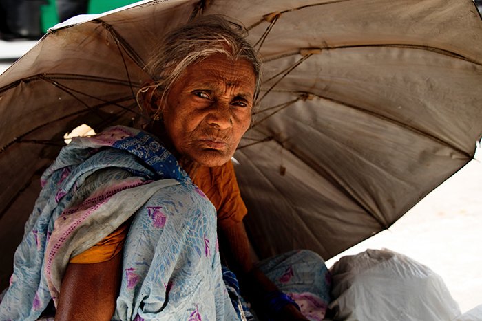 An old woman hiding under an umbrella from the sun - best quality light of day for portraits 