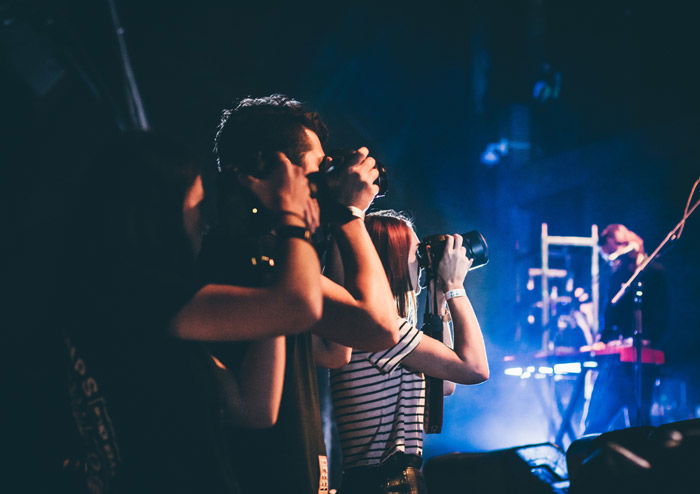 A group of photographers shooting music festival photography by the side of the stage