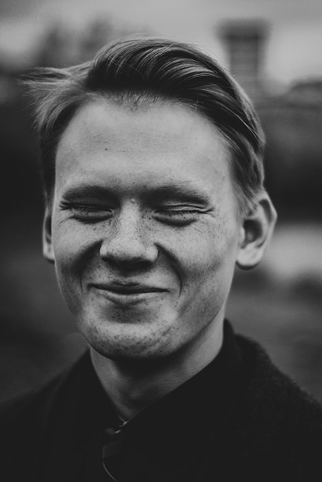 A black and white portrait of a man smiling natural - how to smile for pictures