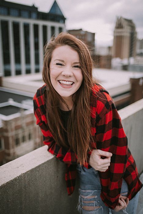 Fun portrait of a laughing female model posing on an urban rooftop - how to smile for pictures